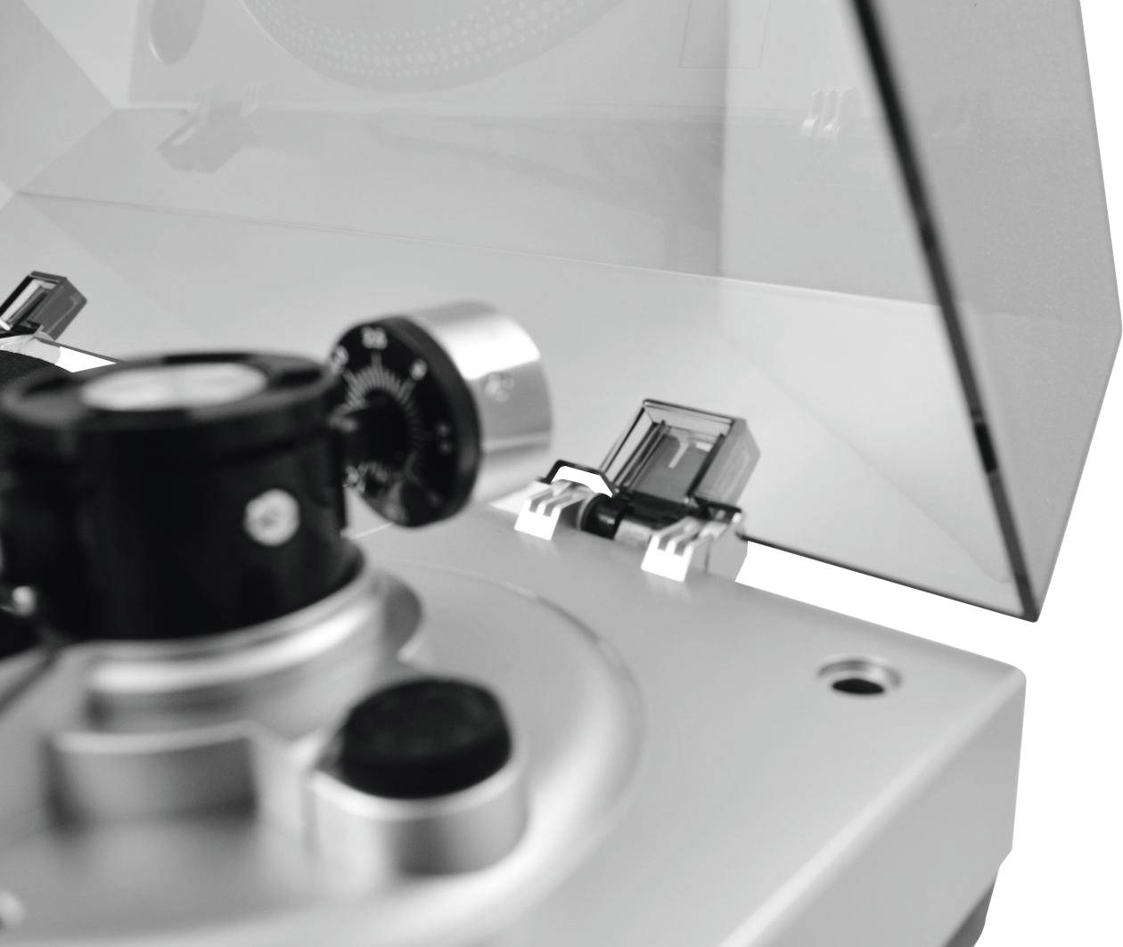 Close-up of a record player with an open transparent lid. Focus on the tonearm area.