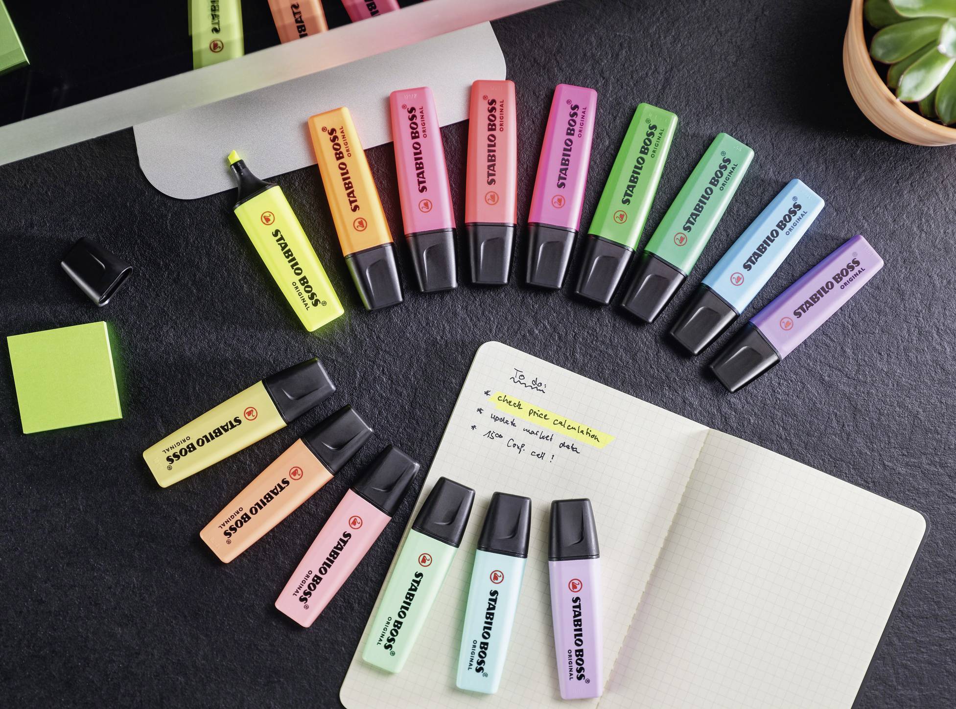 A selection of colourful highlighters on a table surround an open notebook with handwritten notes.