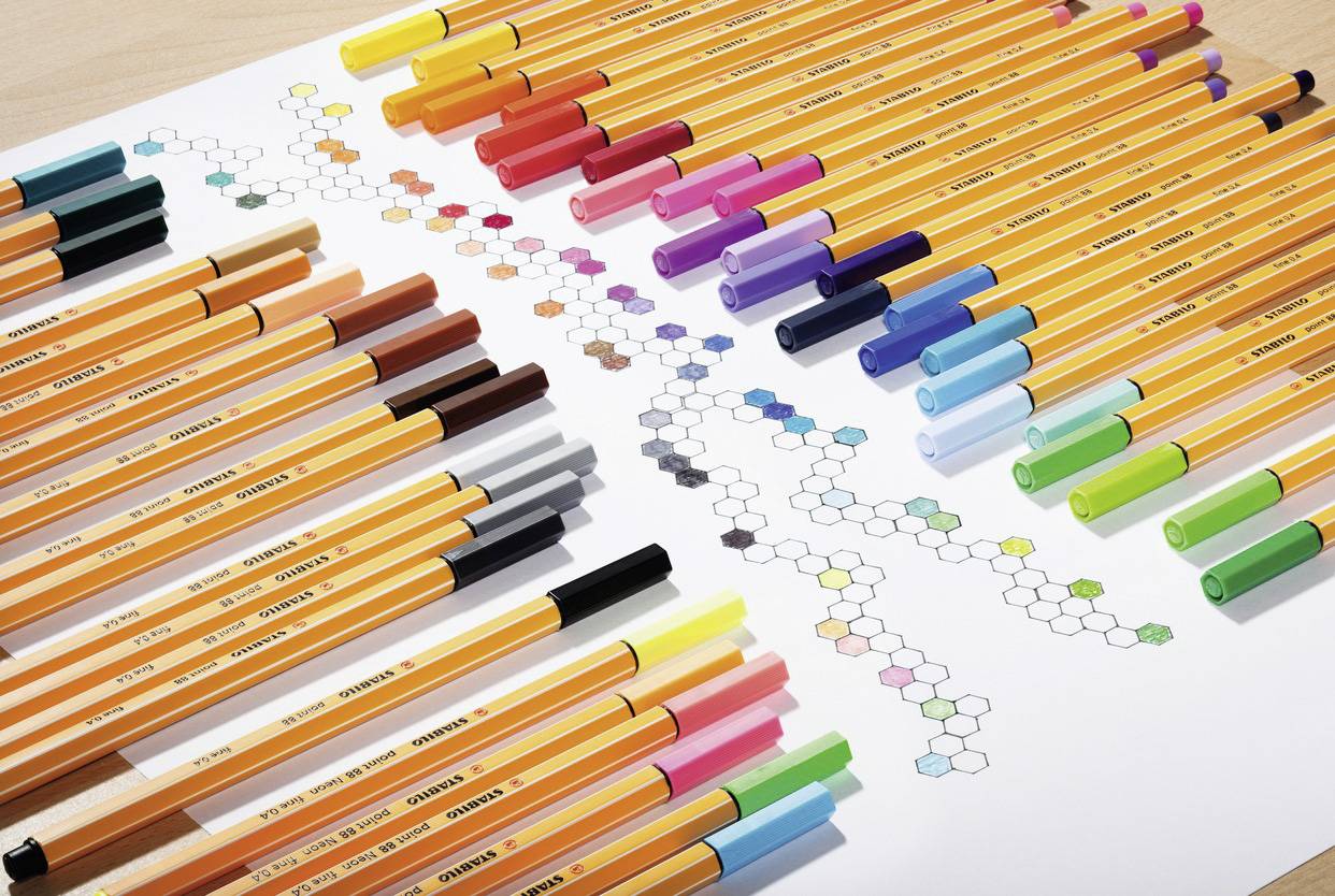 On a table, coloured pencils in various shades are neatly arranged. Beside them, chemical structures are sketched.