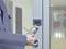 A person holds an RFID card up to an access control device on a glass door to gain entry to a building.