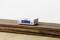 A small, white portable radio sits on a wooden table, displaying 'Koffee Time to Chill' on its screen.