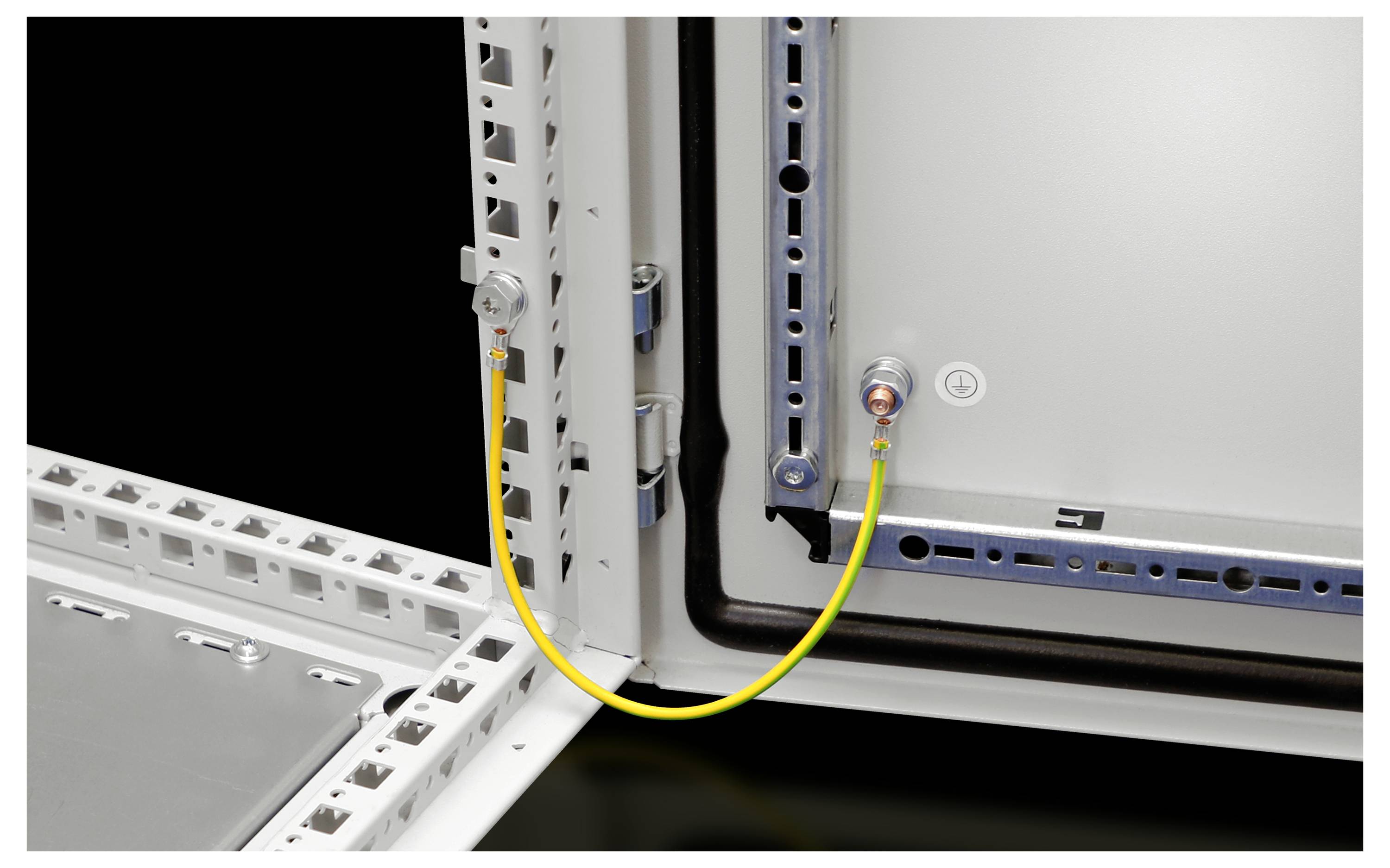 An open electrical cabinet reveals a yellow earthing cable connecting two attachment points to the metallic frame.