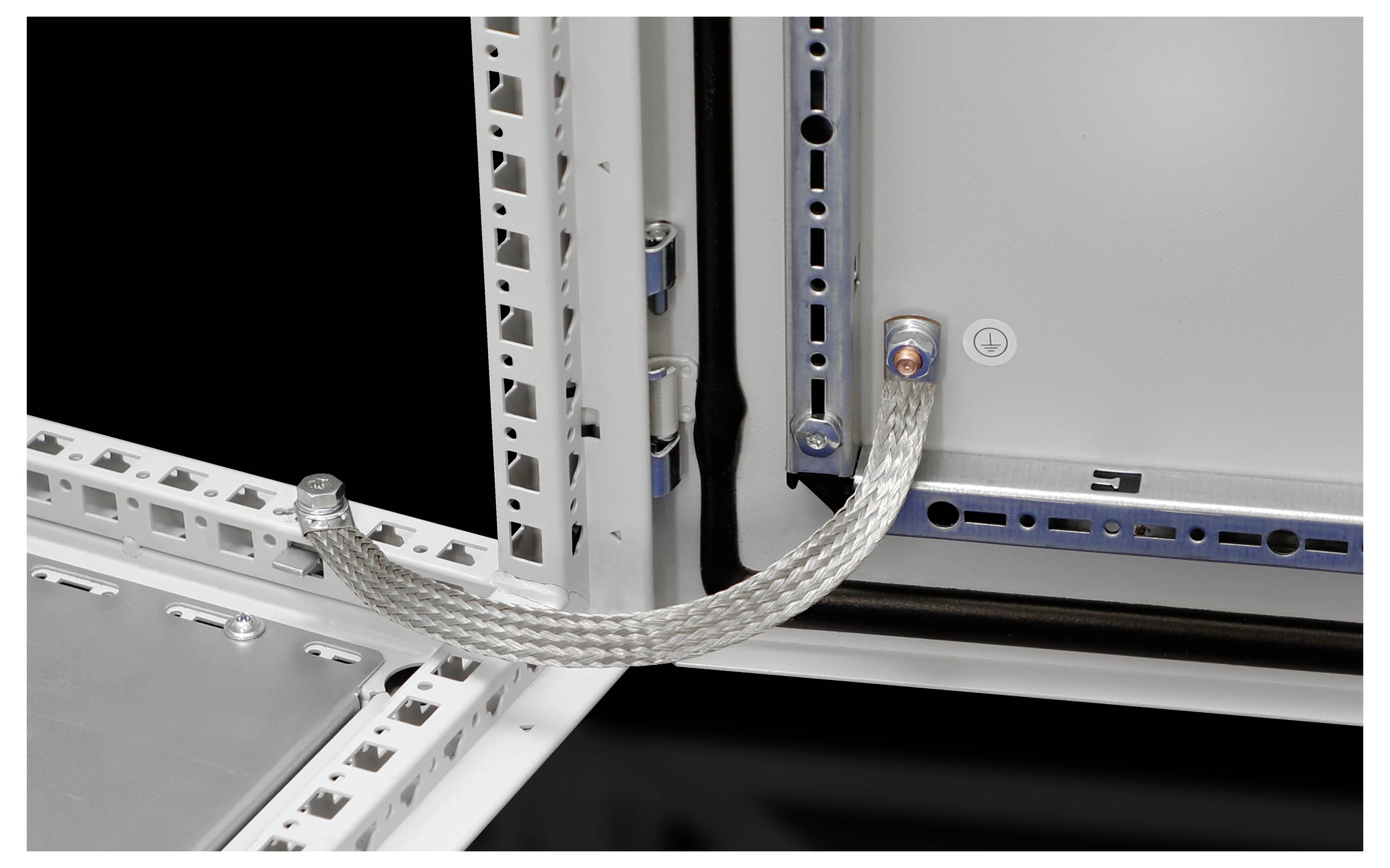 A flexible, silver braided cable is attached to a metal frame and connects various metallic structures to one another.