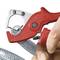 A red pipe cutter is cutting a flexible, transparent hose. A hand is holding the tool to guide the cut.