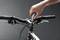 A hand tightens the screw on the stem of a bicycle handlebar using an electric screwdriver.
