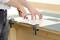 A person is cutting paper with a knife on a table secured with clamps.