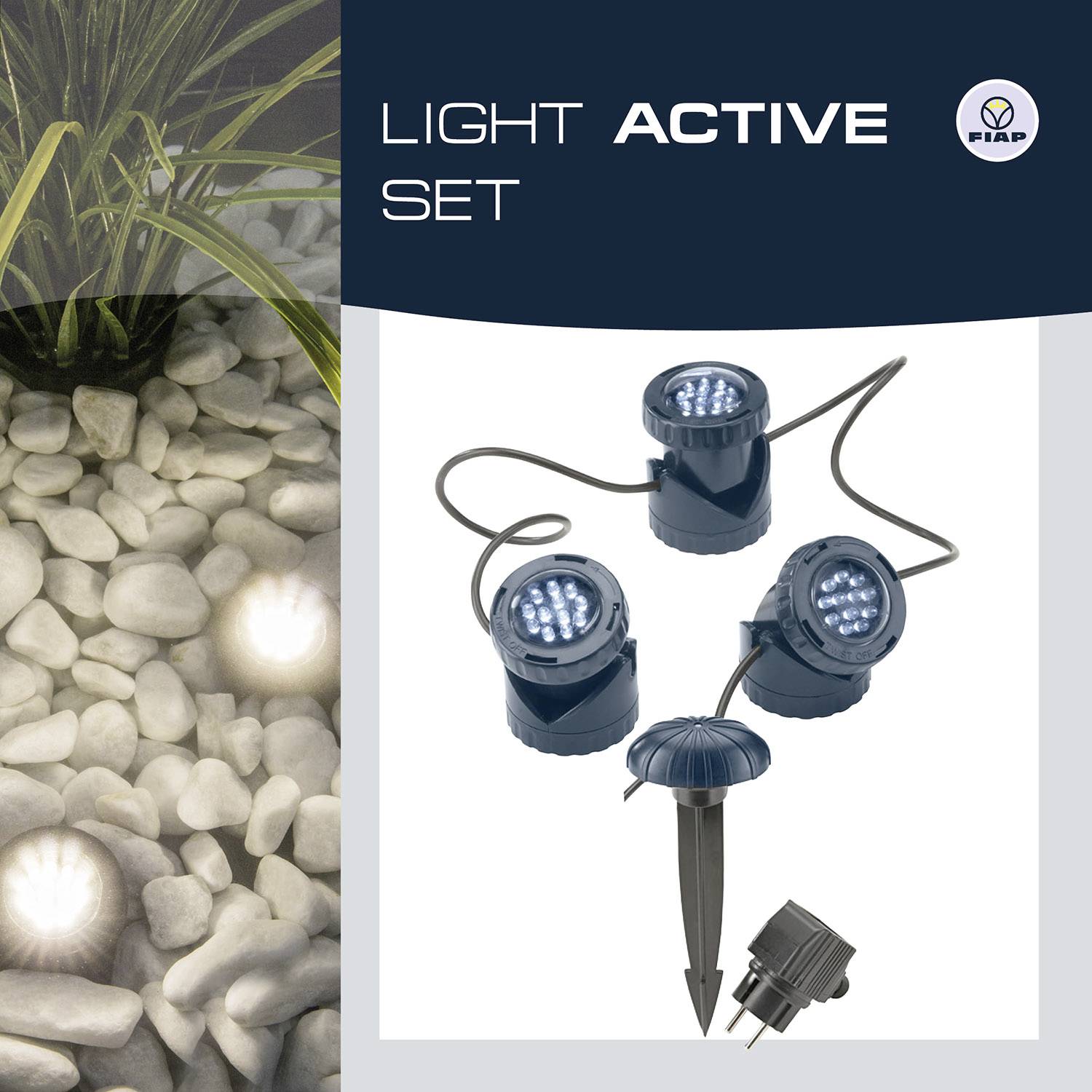 The image shows an outdoor lighting set with three LED spotlights, decoratively positioned next to stones and plants.