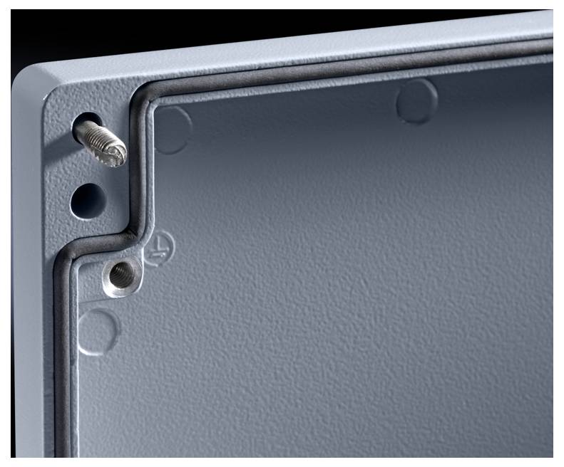 Close-up of a grey, textured inner edge of a metal cabinet with visible screws and a sealing ring in a corner.