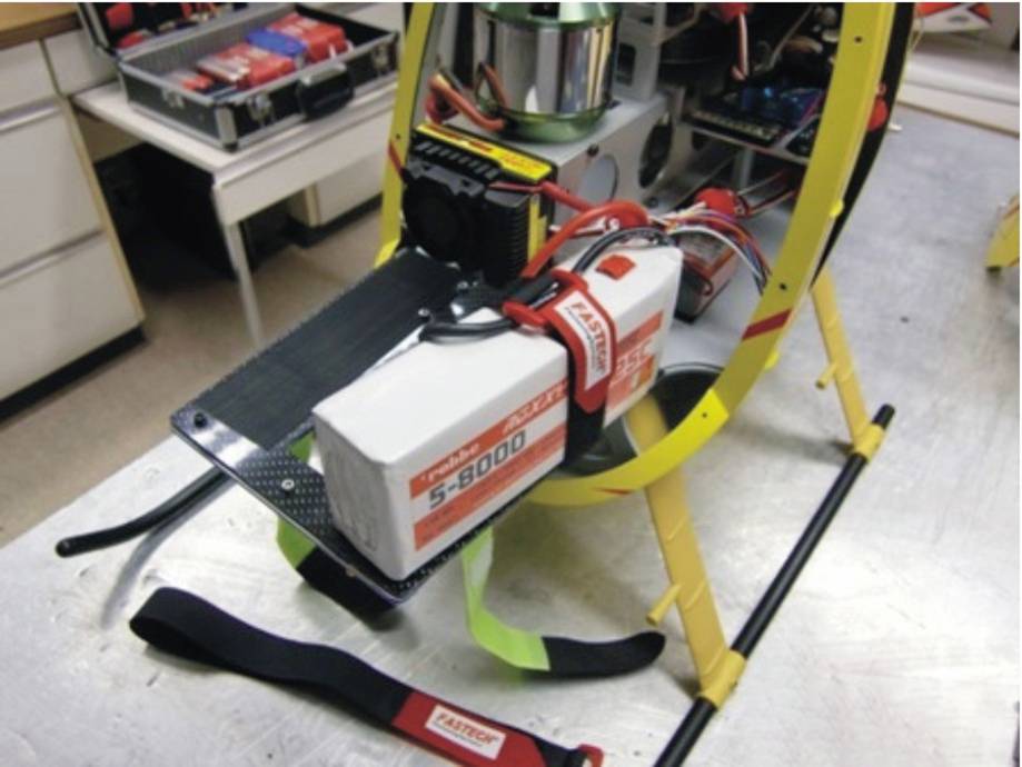 An S-8000 battery mounted on a table, surrounded by cables and technical equipment, shows a technological setup.