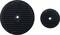 Two black, round rubber discs with textured surfaces lying side by side. A larger disc on the left, a smaller disc on the right.