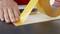 A hand is sticking yellow adhesive tape onto a flat surface.