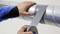 A person is sticking silver adhesive tape onto a metal pipe.