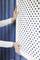 A person is installing a white lattice in front of a blue wooden wall.