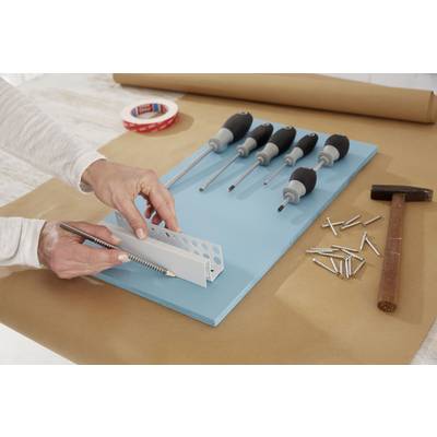 A person is mounting a white metal angle bracket onto a blue plate, surrounded by screwdrivers, screws, and a hammer.