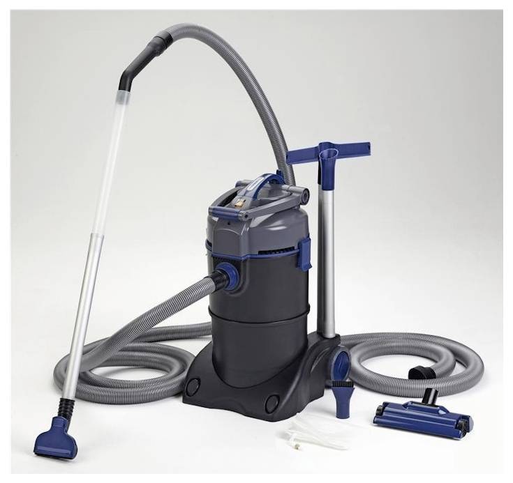 A pond vacuum cleaner is displayed on a wooden deck beside a pond, featuring a hose, nozzle attachments, and a water inlet, set in a green landscape.