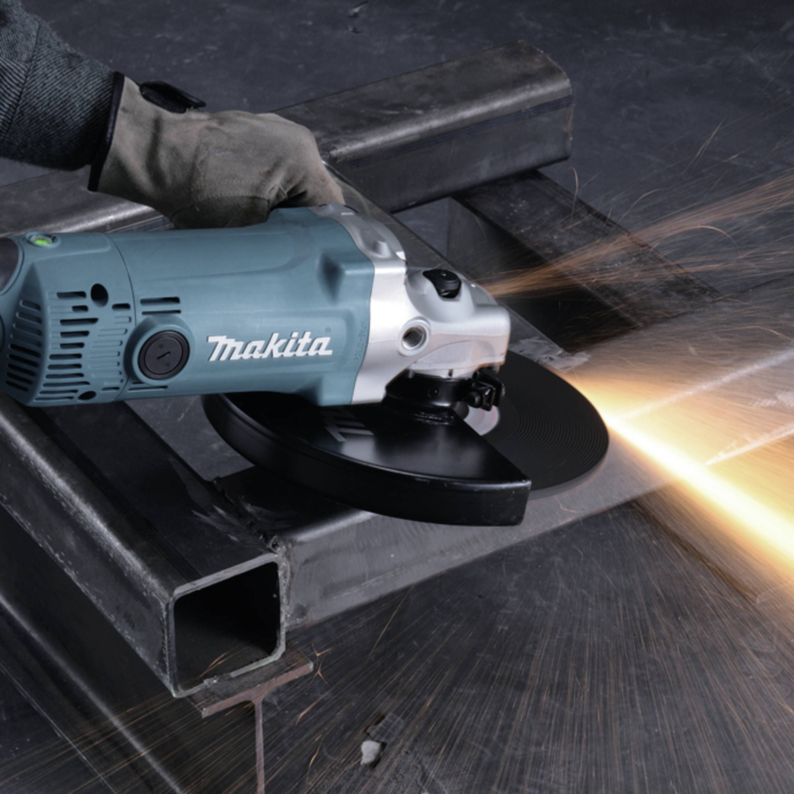 A person is grinding metal with an angle grinder. Sparks are flying from the worked metal surface.