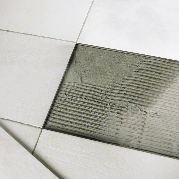 Tiling: White tiles are laid on cement adhesive, which has been applied using a notched trowel.