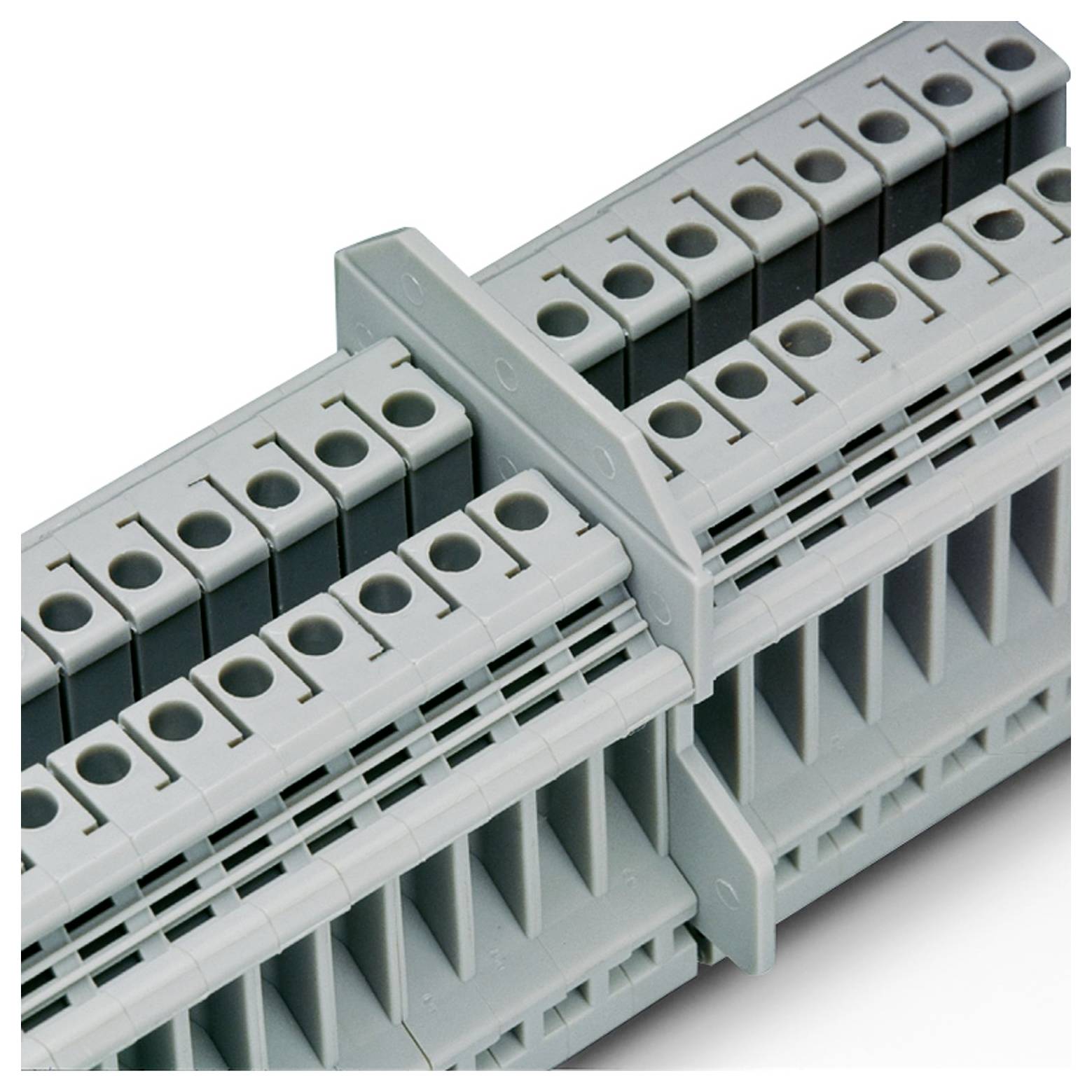 'A grey terminal block with multiple connection points, used for wiring in electrical panels, seen in close-up.'