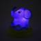 A luminous night light in the shape of a cheerful, sitting elephant on a round base, emits a blue light.