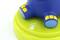 A blue and yellow toy on a green base with a touch symbol, which presumably indicates an interactive function.