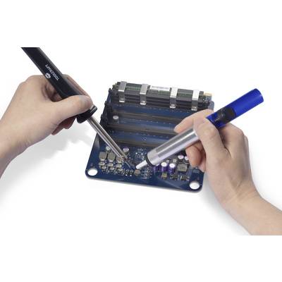 Two hands are working with soldering irons and a desoldering pump on a blue printed circuit board. Various electronic components are visible.