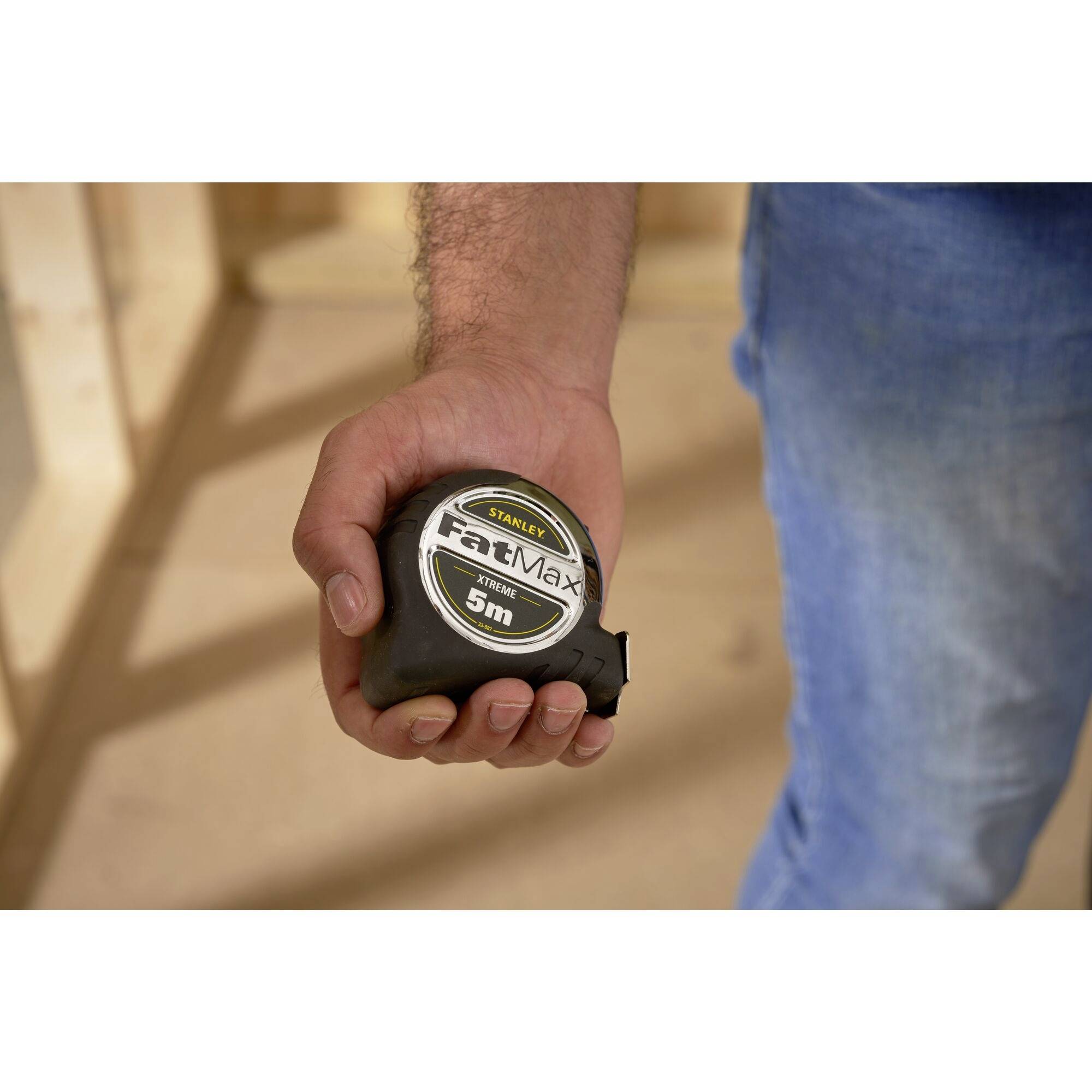 A person is holding a tape measure in their hand. The tape measure is from the 'FatMax' brand and shows a length of 5 metres.