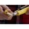 Two hands are holding a yellow utility knife and a replacement blade dispenser. A blade is being changed. Background: checked shirt.