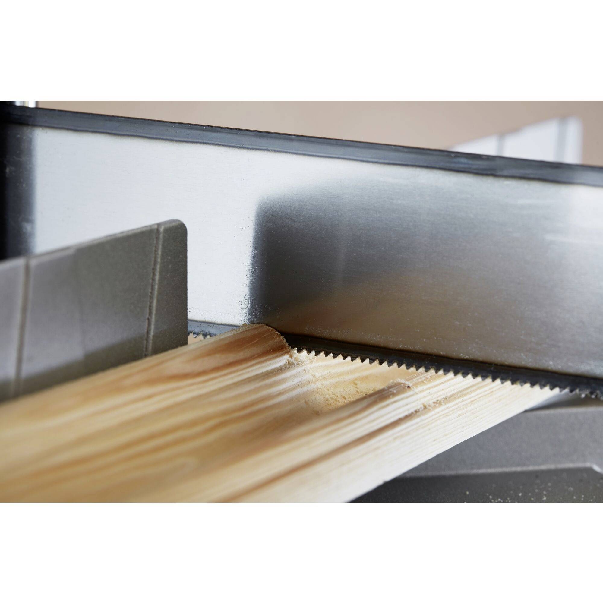 A wooden board is being cut by an electric saw with rotating teeth, showing a precise and clean cut on the surface.
