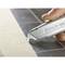 A hand is holding a silver Stanley 99E utility knife on a grey surface, ready to cut.