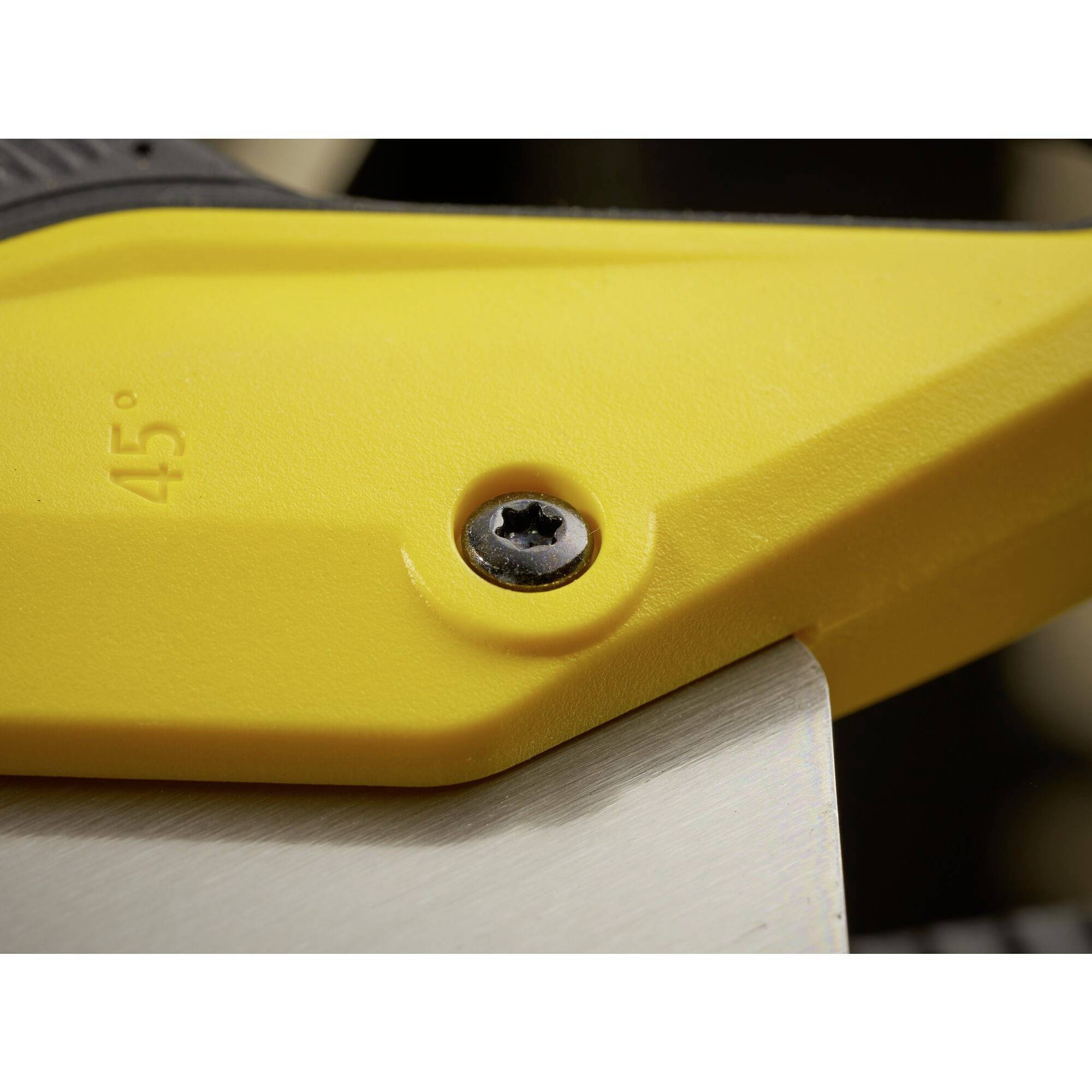 Close-up of a yellow saw with a screw head. The blade is metallic and shows a 45-degree marking.
