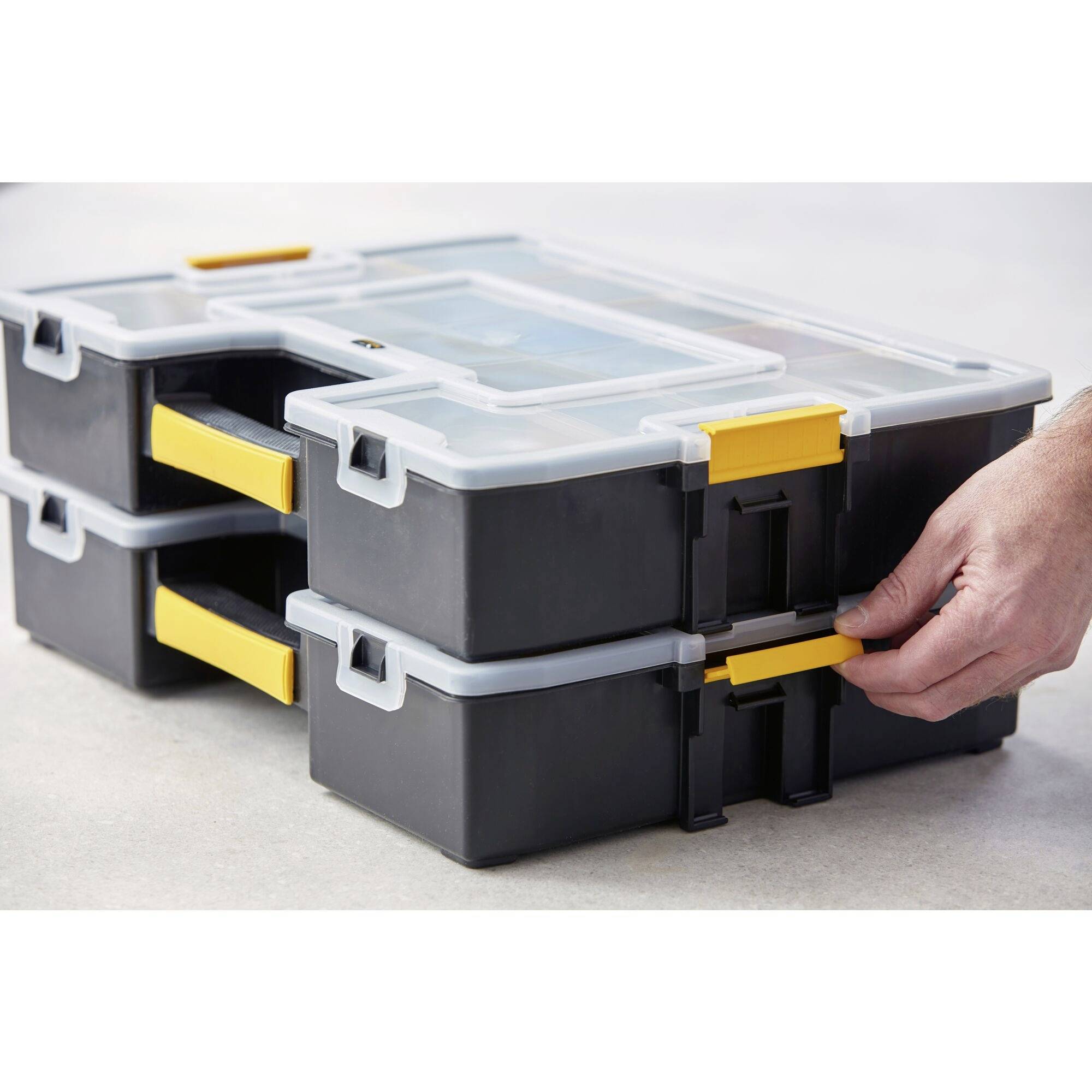 Three stacked toolboxes with a yellow handle, a hand pulling out one of the boxes.