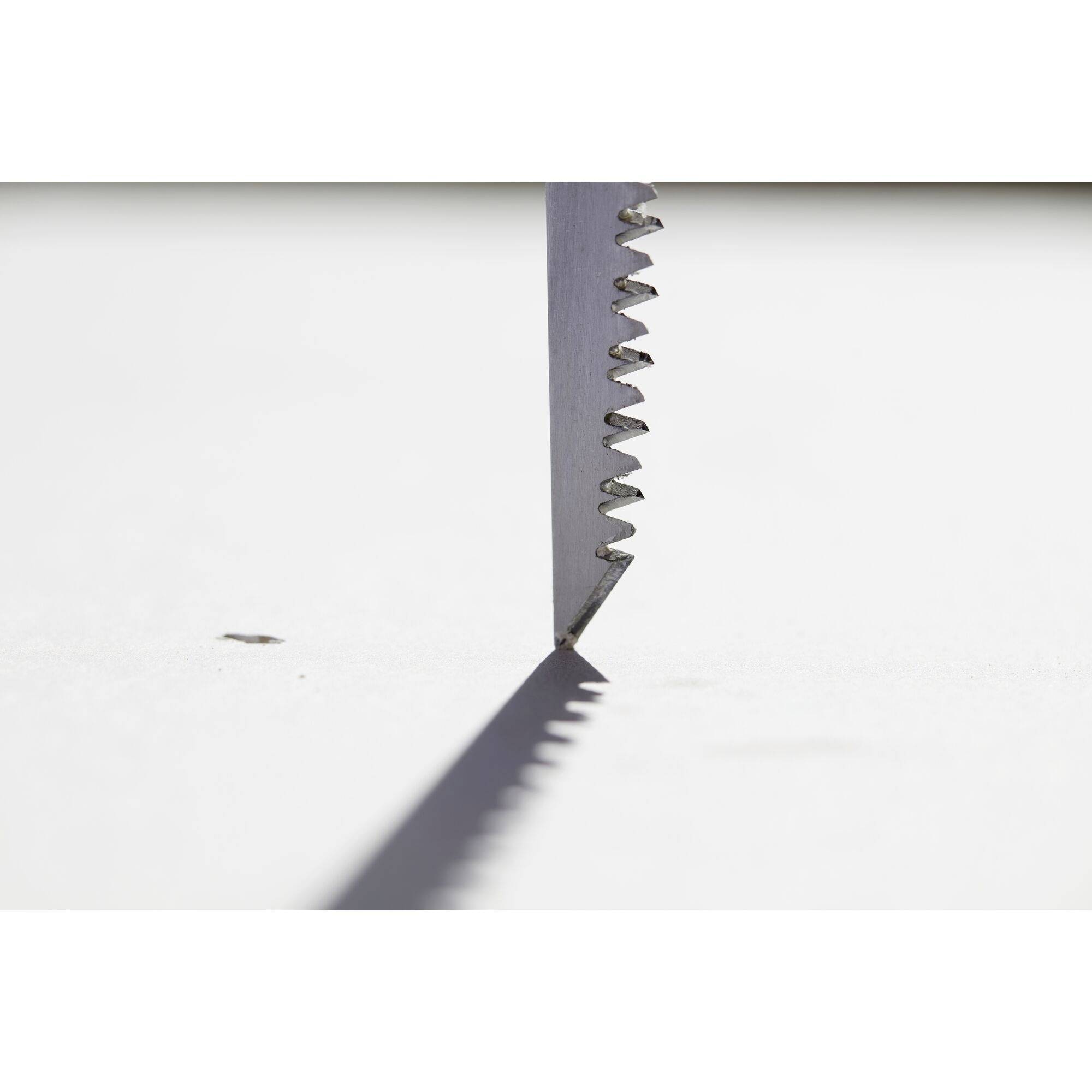 Close-up of a saw blade on a white surface, casting a shadow.