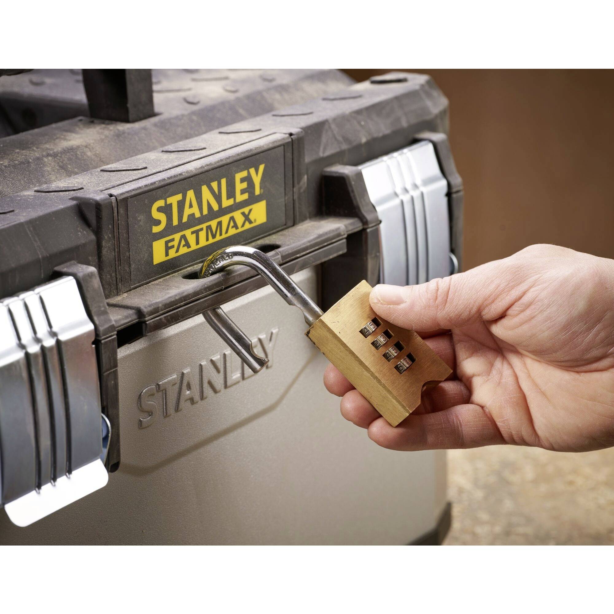 A hand opens a combination lock on a grey toolbox with the inscription 'Stanley Fatmax'.