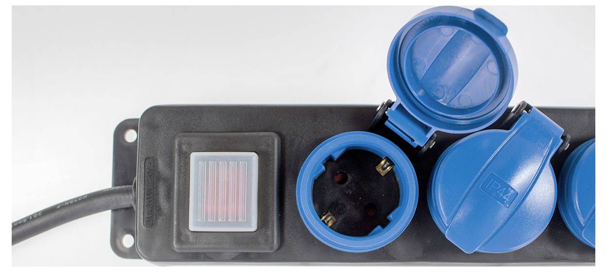 A black multi-socket extension lead with a switch and blue, partially covered safety shutters.