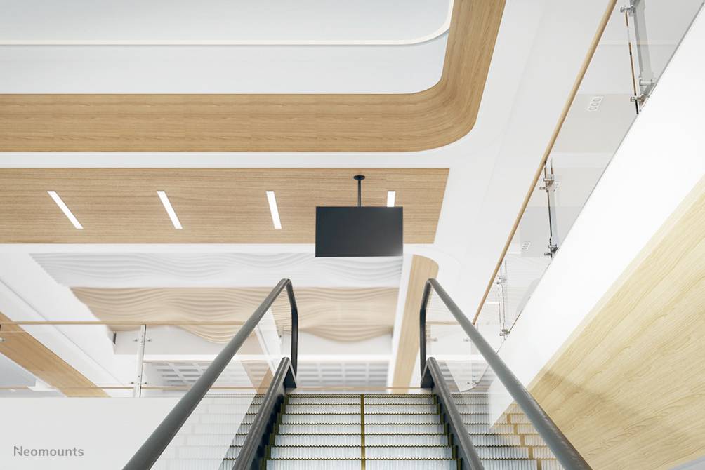 Escalator in a modern building with a wooden ceiling and a black screen at the top centre.