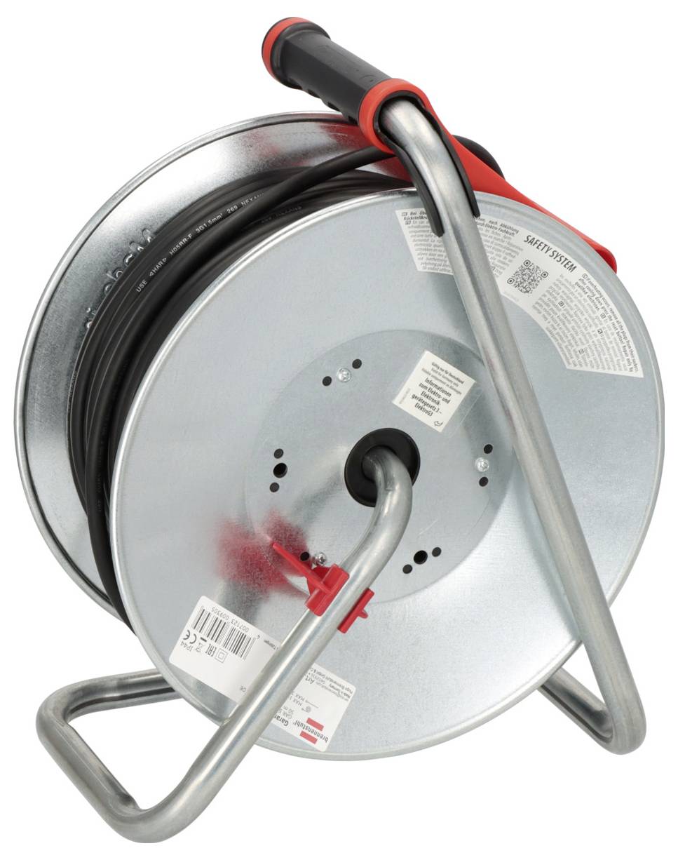 A metal cable reel with a handle, holding a coiled black cable. The reel has labels with text and is supported by a metal frame.