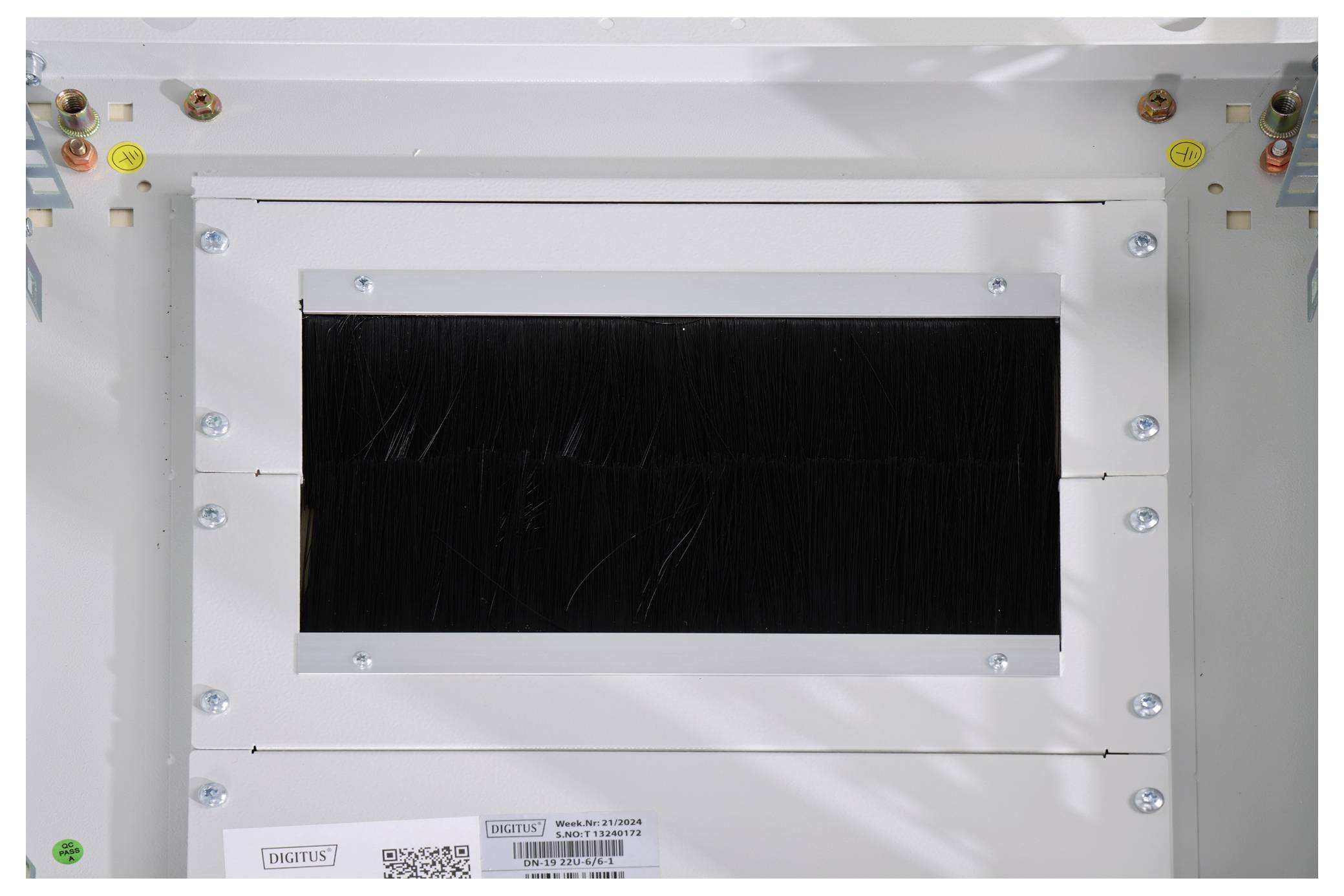 A rectangular, white technical module with a black brush seal and visible screws on the sides; surrounded by cable connections.