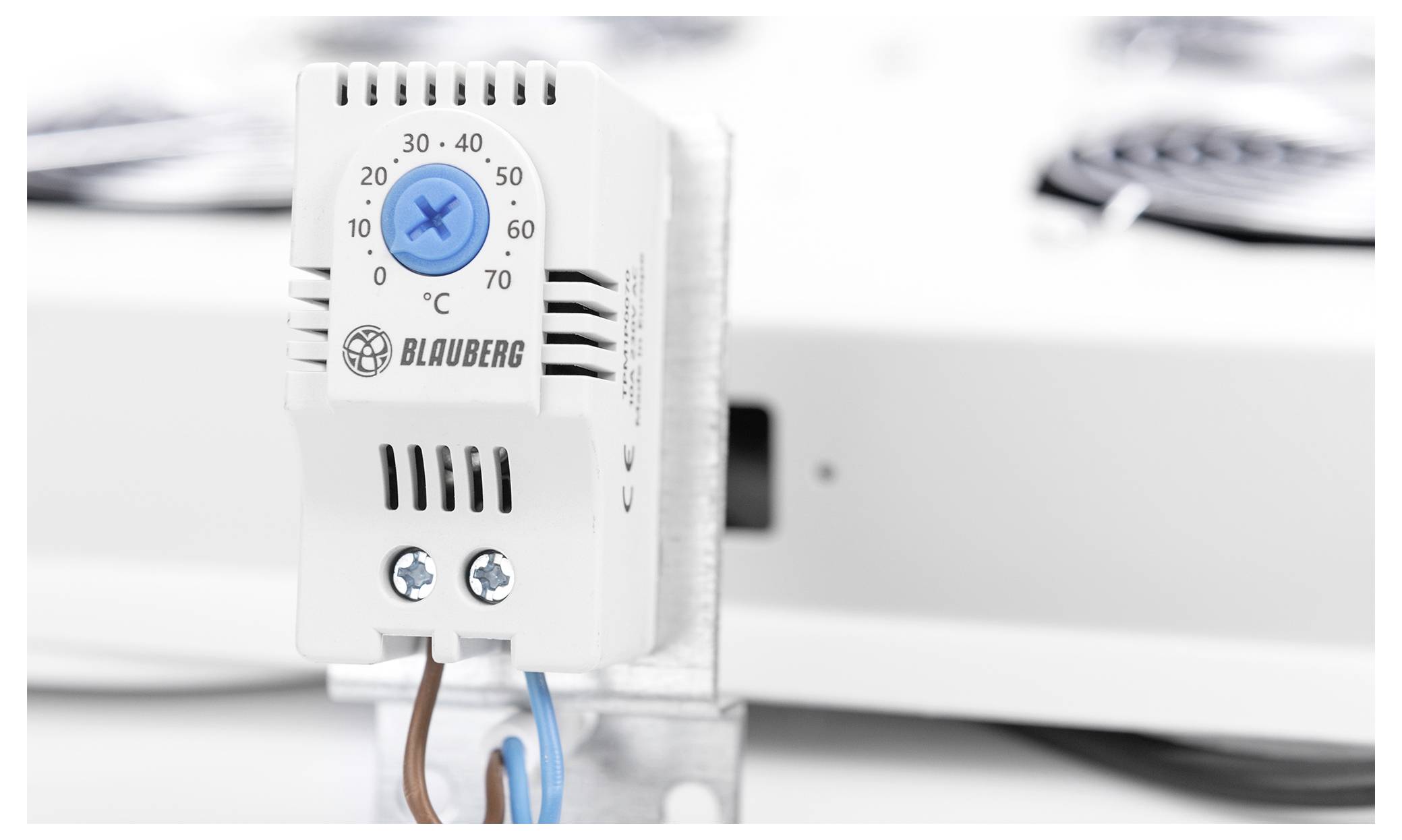 A thermostat with a blue dial set to 25°C, mounted on a metal bracket.