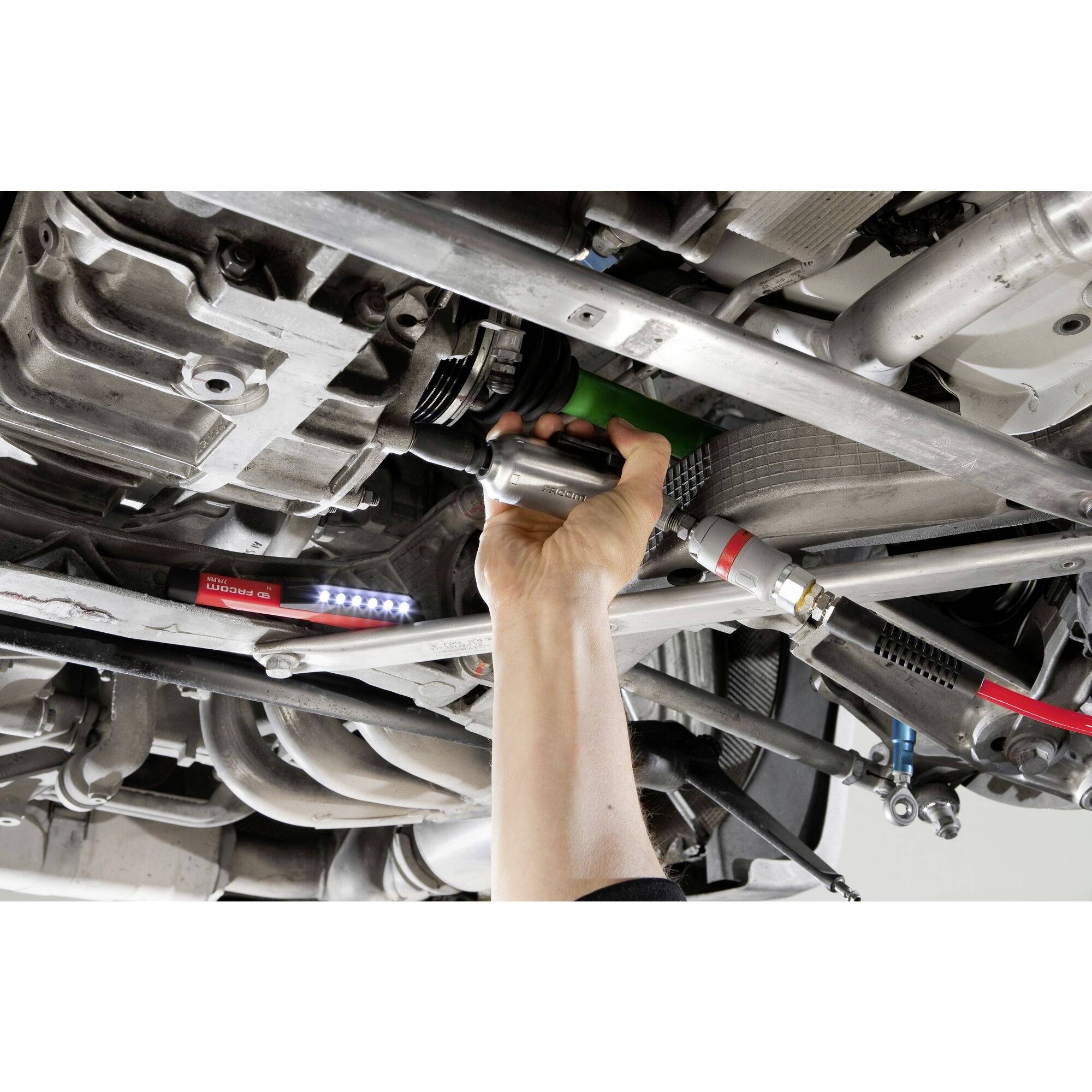 'A mechanic is working underneath a car, checking the engine bay and using a torch to illuminate the area, held by a hand.'