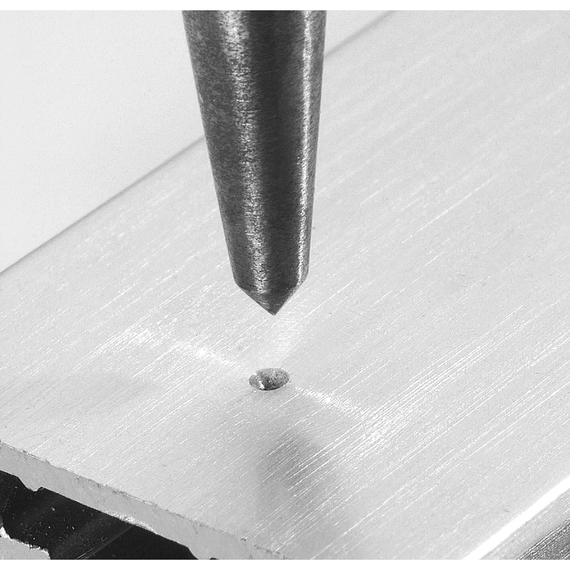 Metal tip of a tool pressing into a piece of aluminium to create an indentation.