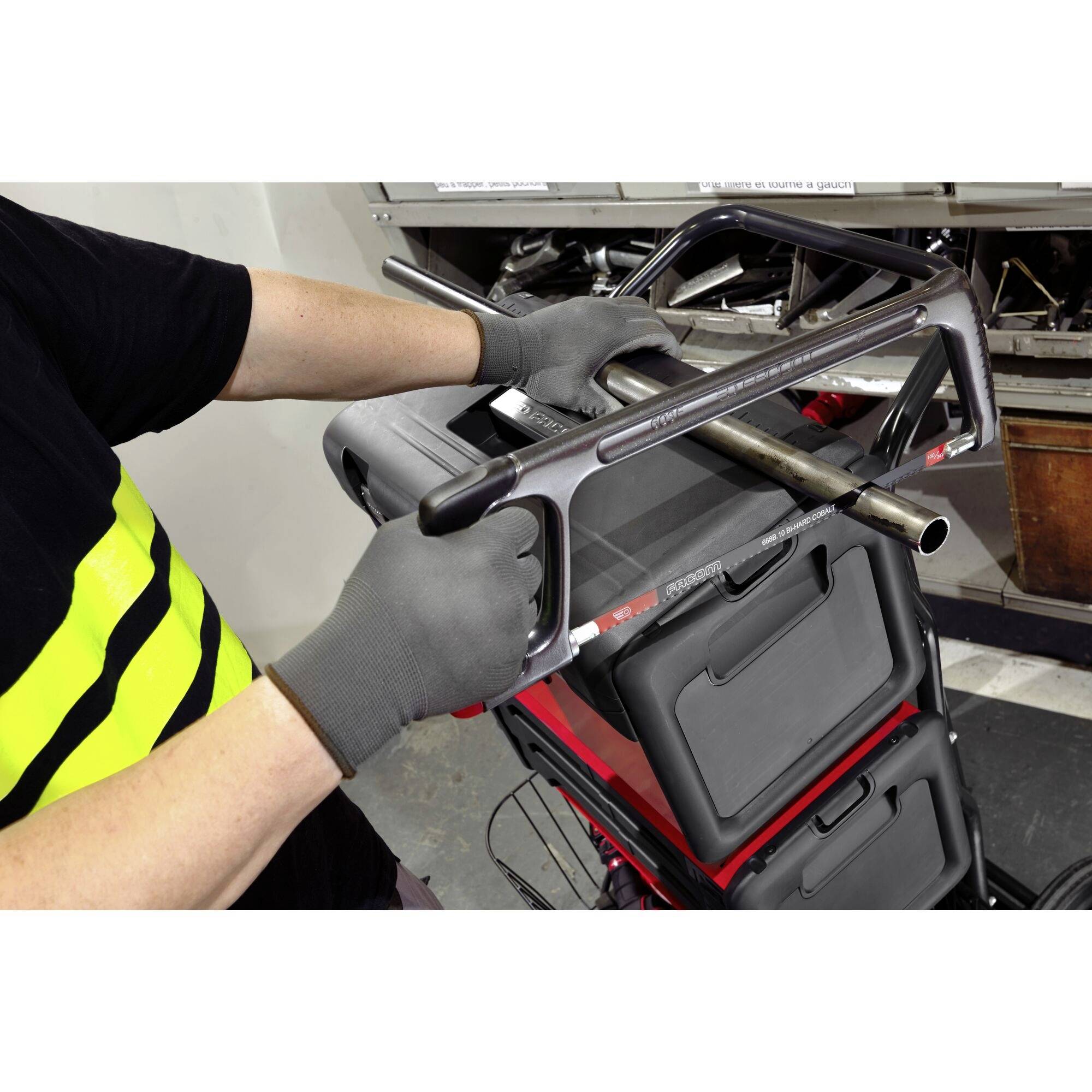 A person wearing gloves is mounting a bicycle handlebar on a bike. Workshop-like equipment can be seen in the background.