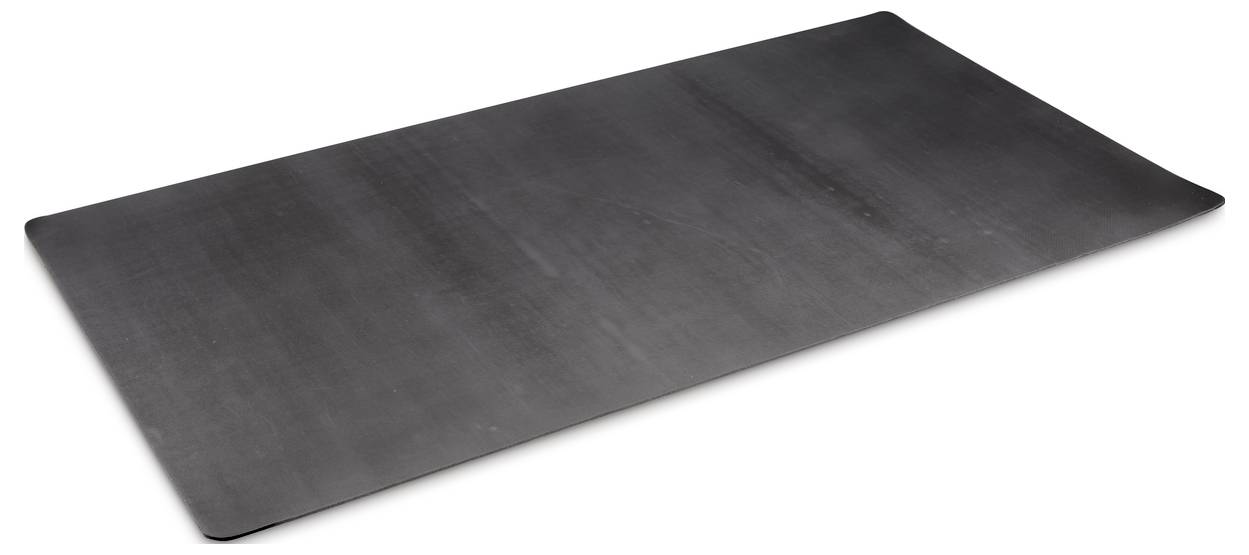A large, black, rectangular rubber mat is lying on a white surface.