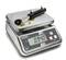 A digital kitchen scale with a small cylinder on the weighing surface displays a weight of 0.940 kg on the display.