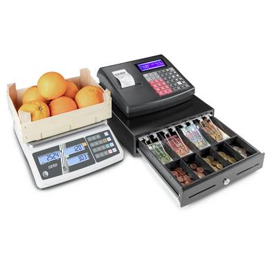 A weighing scale with a crate of oranges on the left, with an open cash register beside it containing banknotes and coins in various compartments.