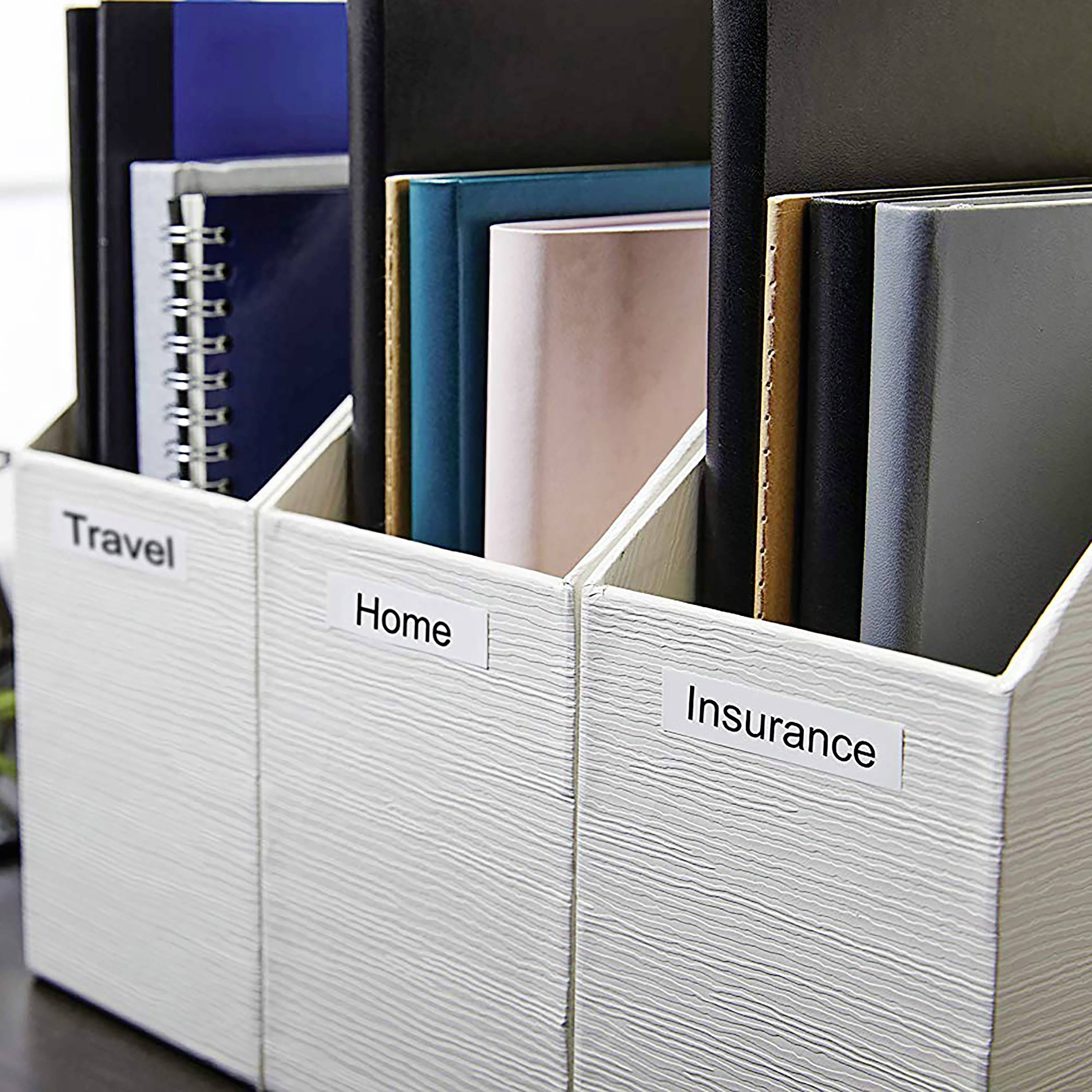 Three ring binders labelled 'Travel', 'Home' and 'Insurance' on a table, each filled with documents.