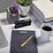 Desk with a laptop, pens, stapler, plant, stack of folders, notebook and a cup of coffee.