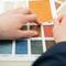 Two hands examine colour samples with a textured surface; focus on blue fabric pattern marked 'TX - 3928'.