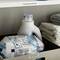 Two bottles of washing liquid and a box of folded towels on a shelf labelled 'Cleaning Supplies'.