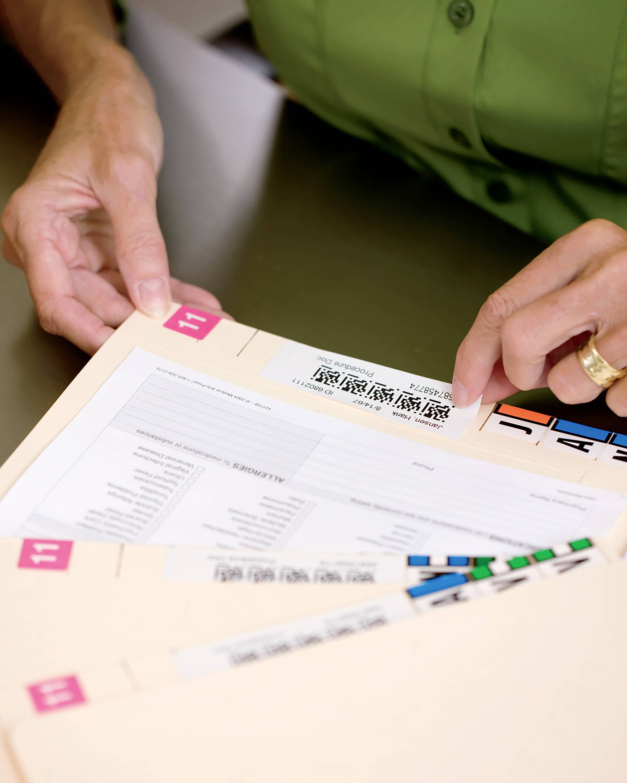 A person's hands are flipping through folders with labels in Chinese script. The folders appear to contain documents.