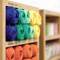 A wooden shelf displays colourful wool balls in various colours. Two price tags show '100% Cotton' and '£ 2.95'.